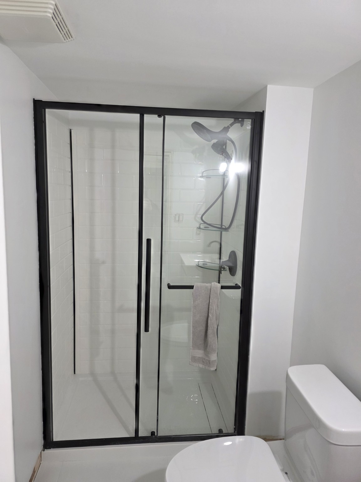 Finished basement bathroom shower and black framed glass enclosure